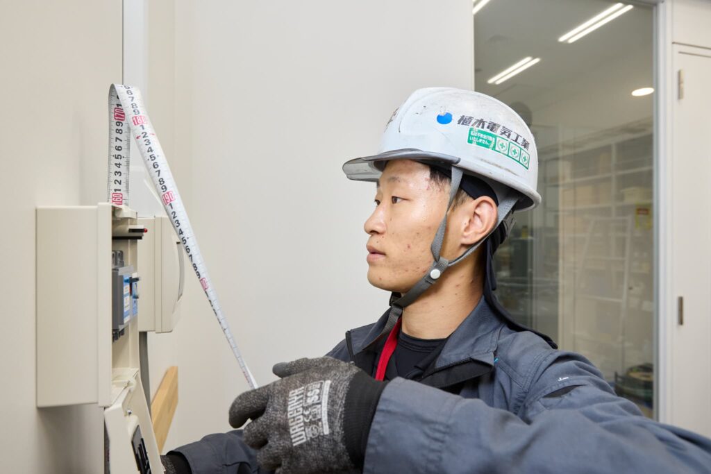 分電盤の高さをメジャーで測定する作業員