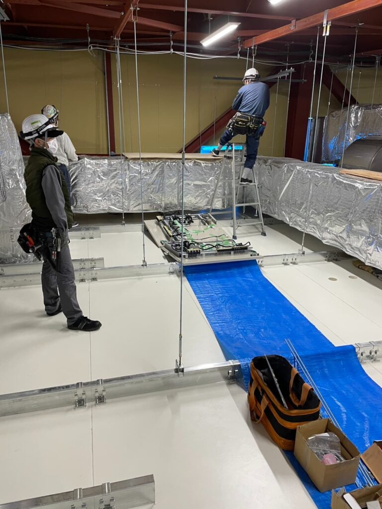 工場の製造ラインで電気工事を行う作業員