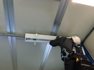 工場の天井で照明を取り付ける電気工事士